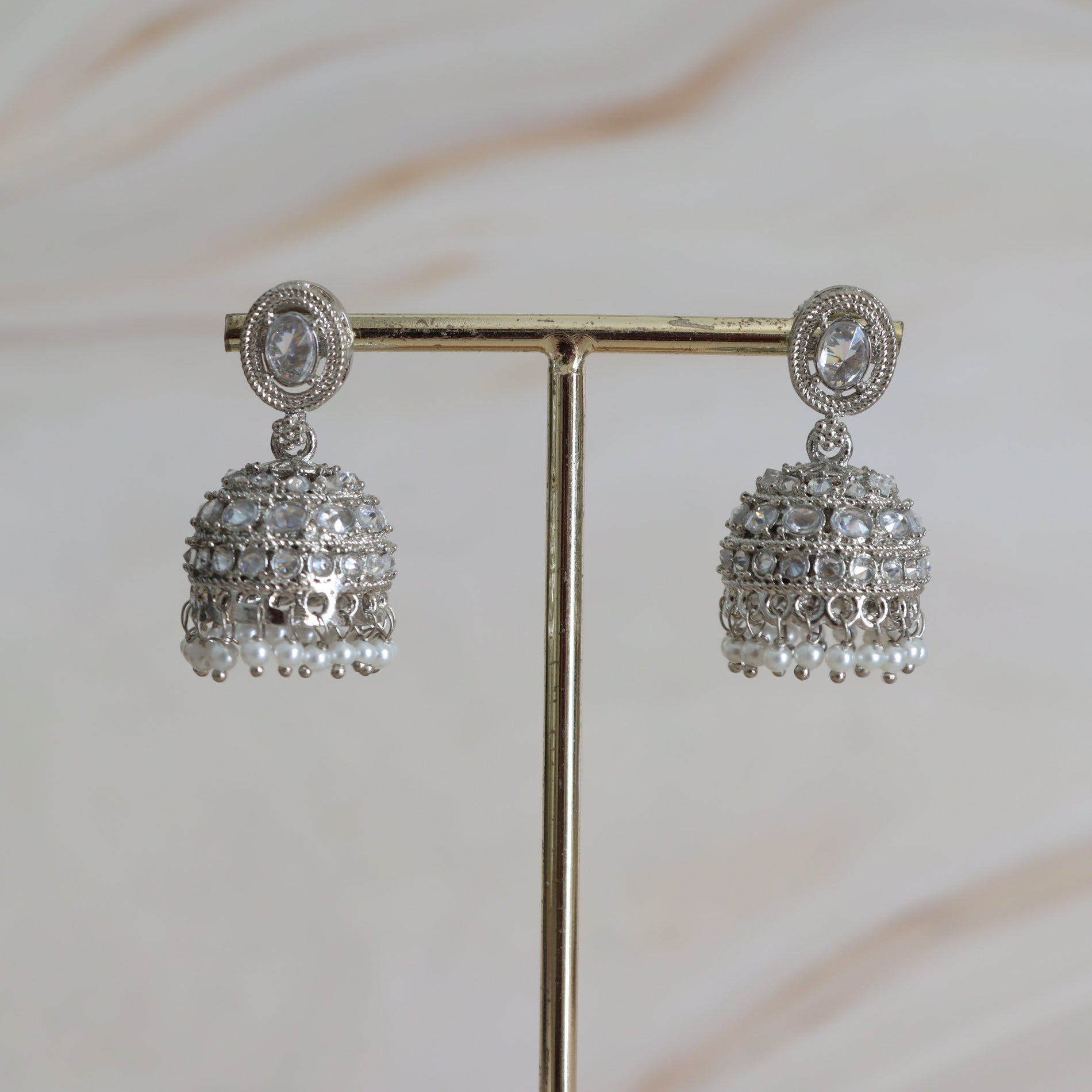 Pair of silver earrings on a stand with a soft blurred background