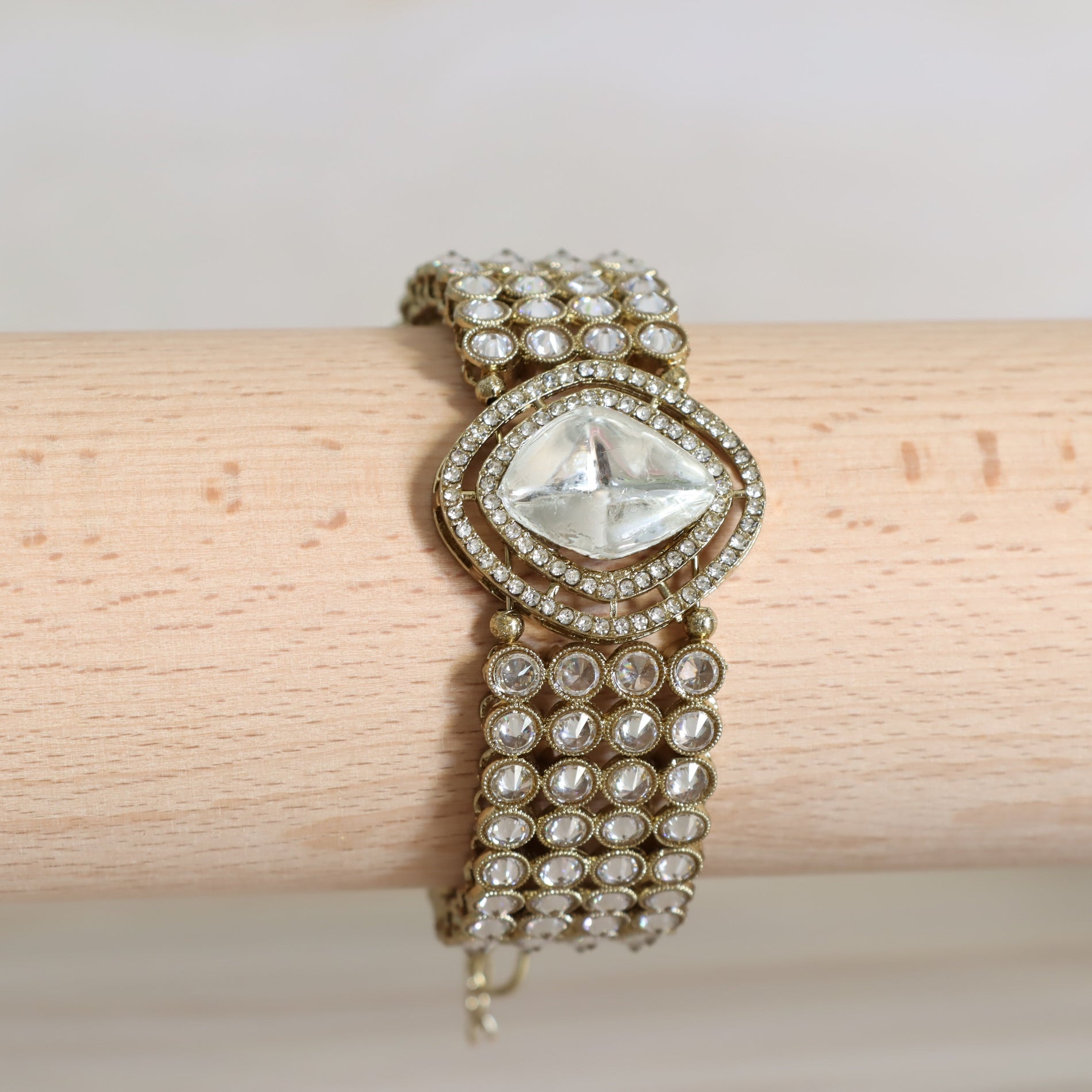 Elegant bracelet with clear gemstone on a wooden stick against a light background