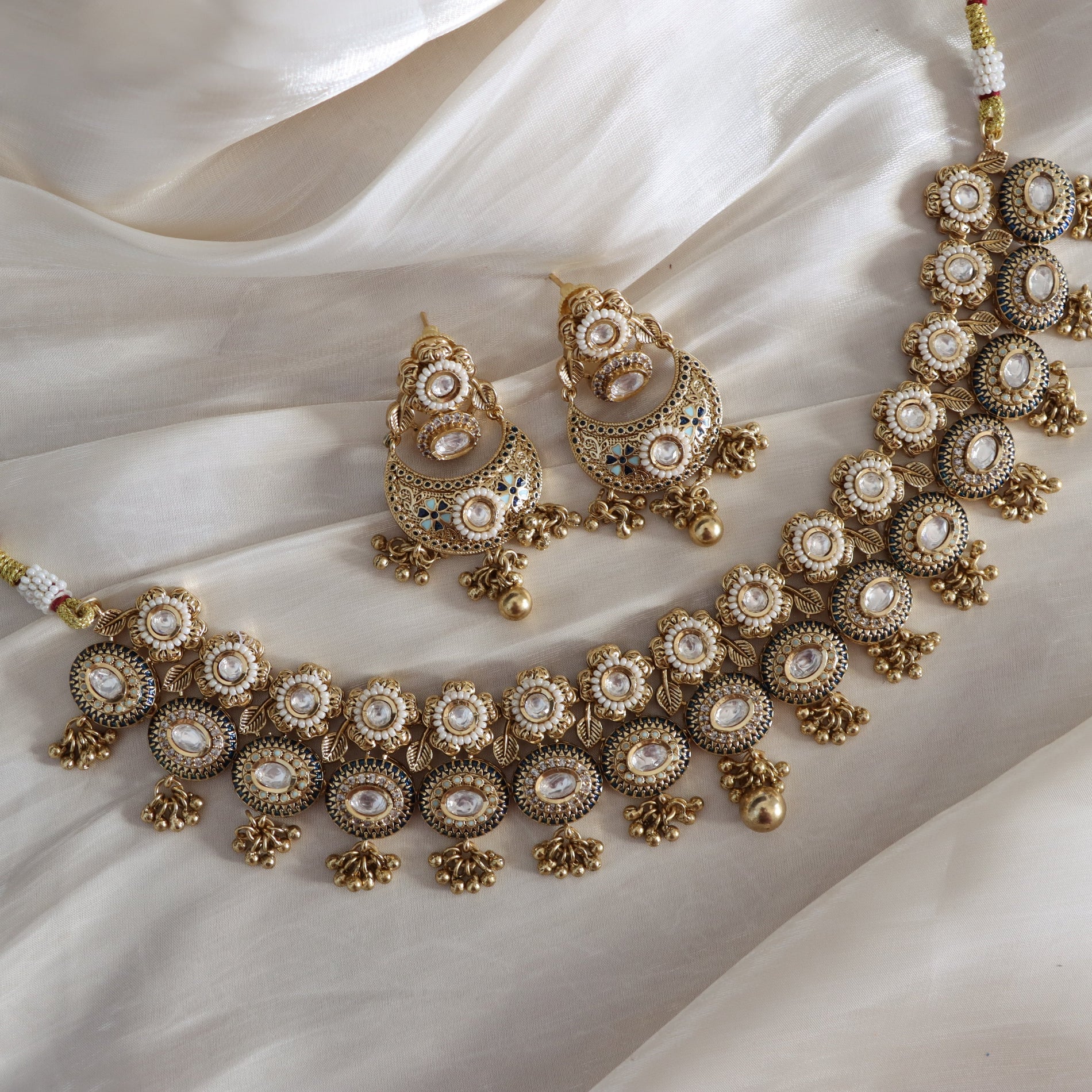 Gold and pearl jewelry set on a white fabric background