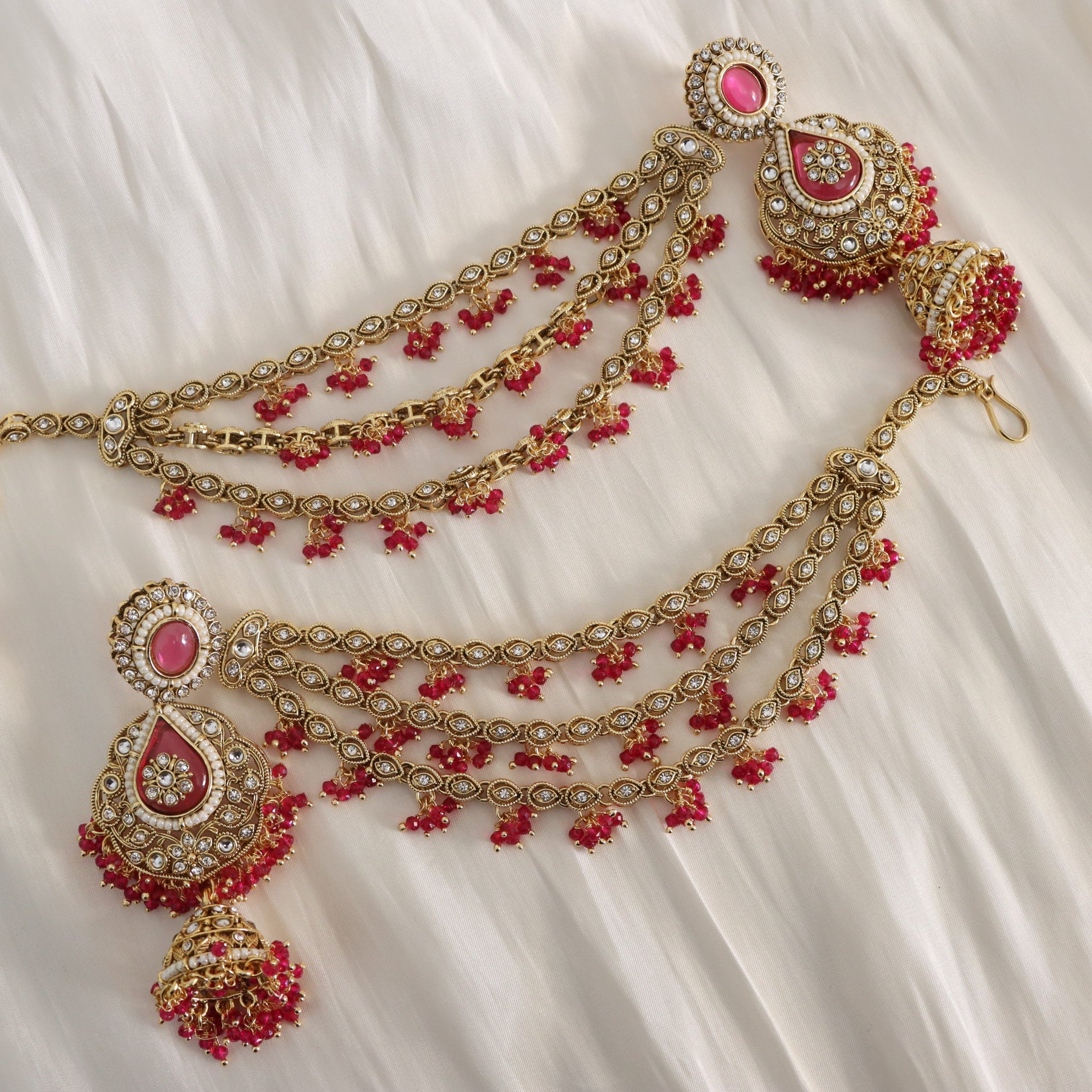 Ornate gold and red jewelry set on a white fabric background