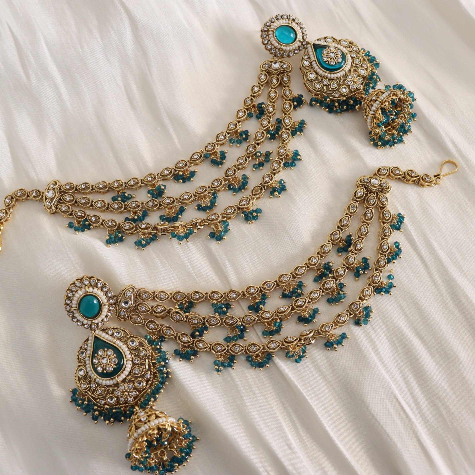 Ornate gold and blue necklace with matching earrings on a white fabric background