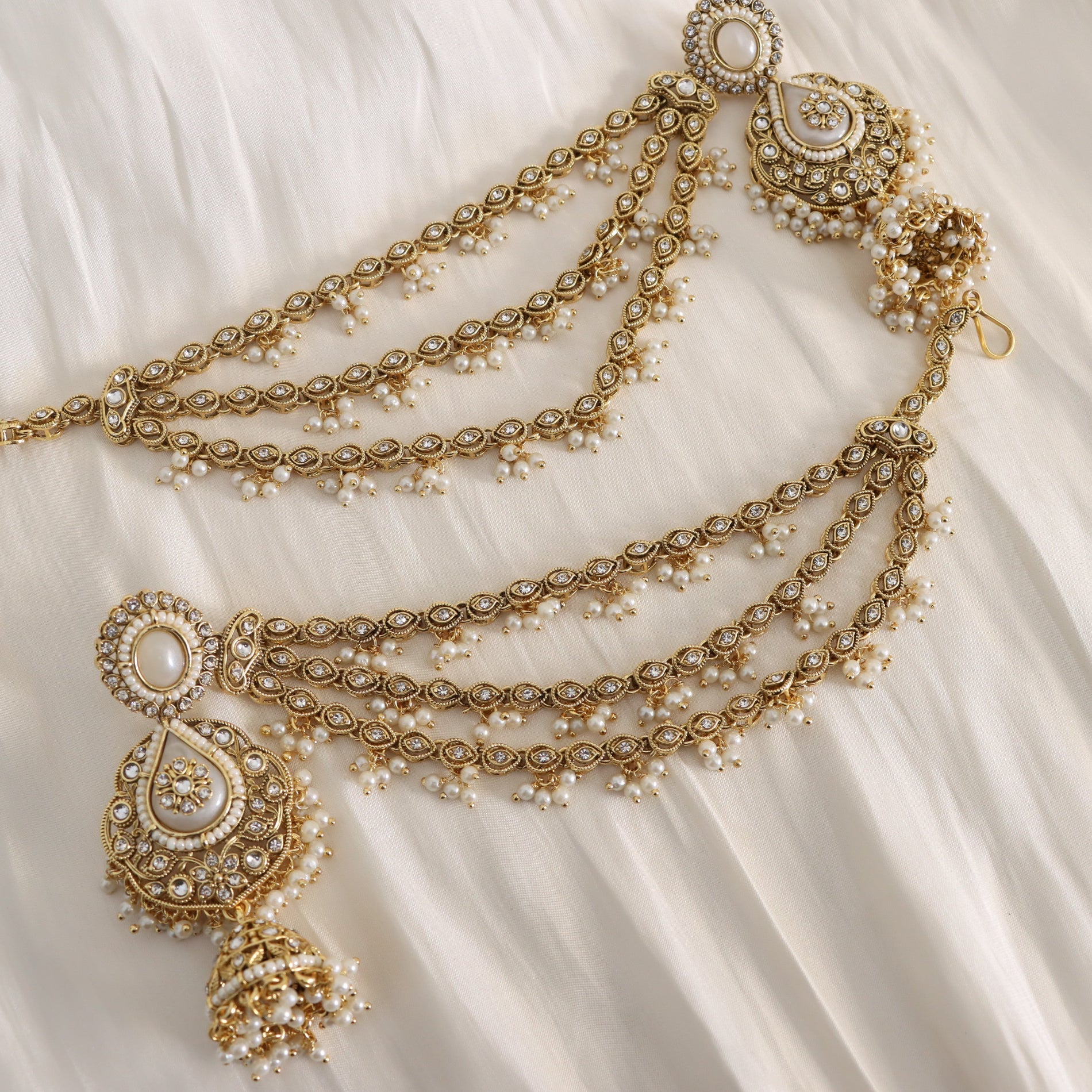 Ornate gold necklace with pearls on a white fabric background