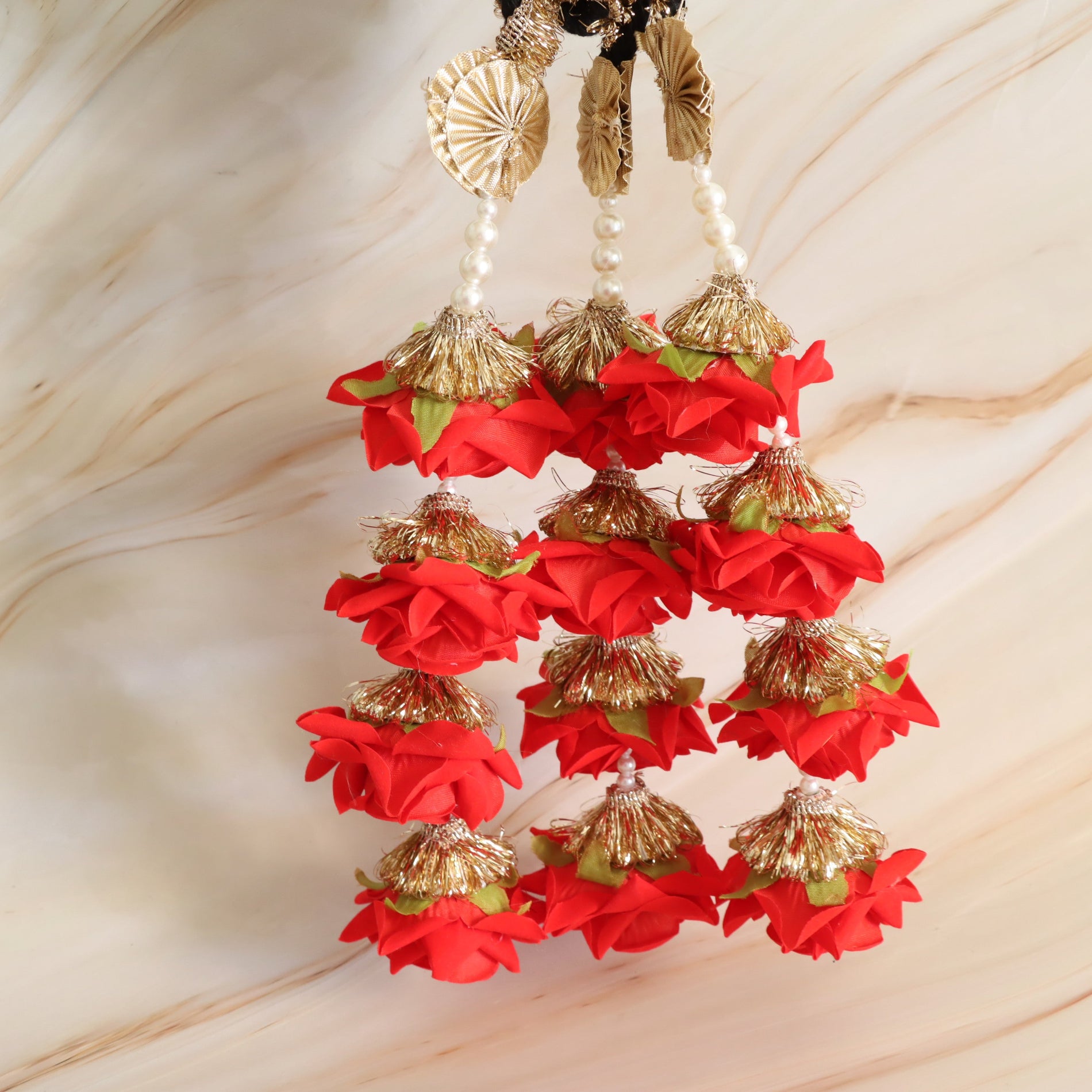 Decorative hanging with red flowers and gold accents on a beige background