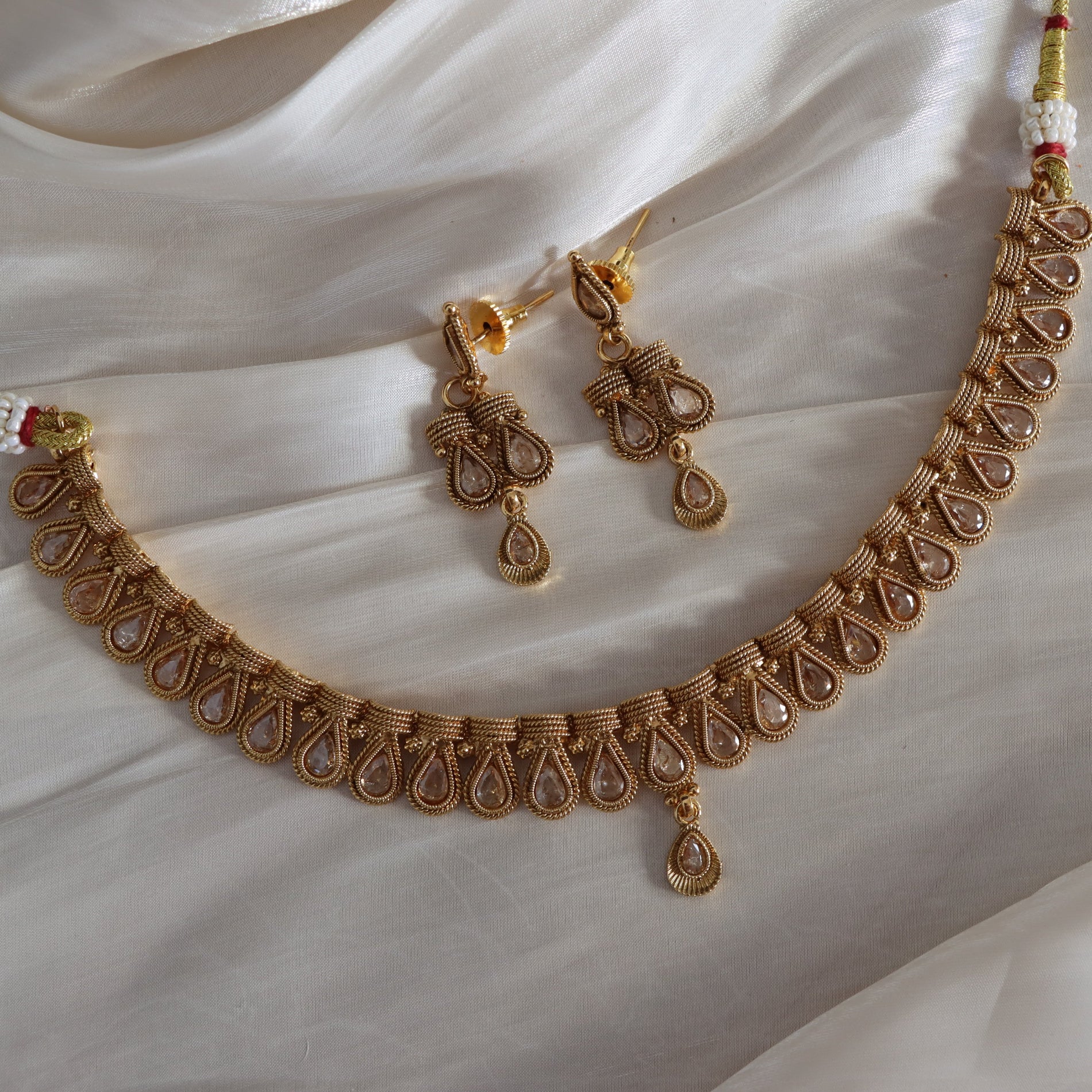 Gold necklace and earrings on a white fabric background