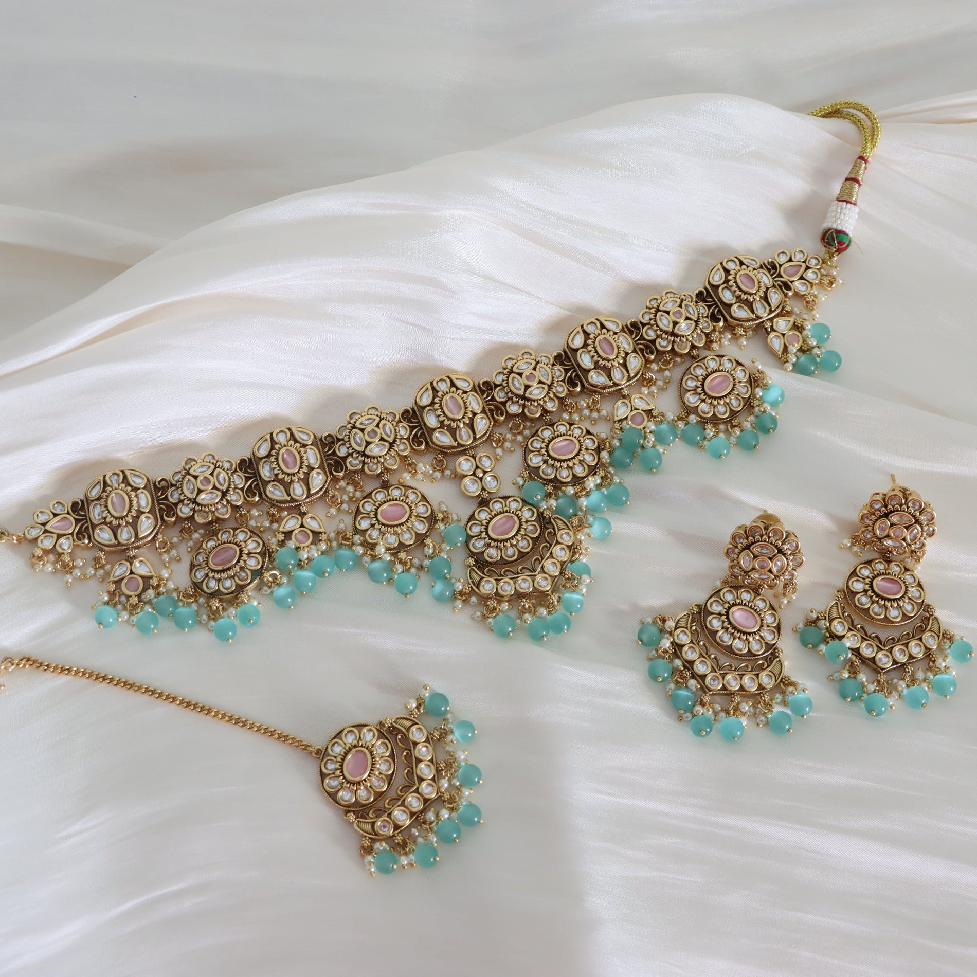 Ornate gold and turquoise jewelry set on a white fabric background
