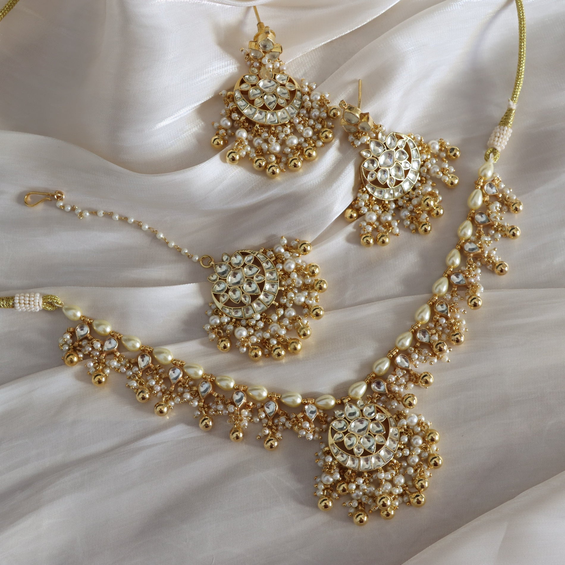 Gold and pearl jewelry set on a white fabric background