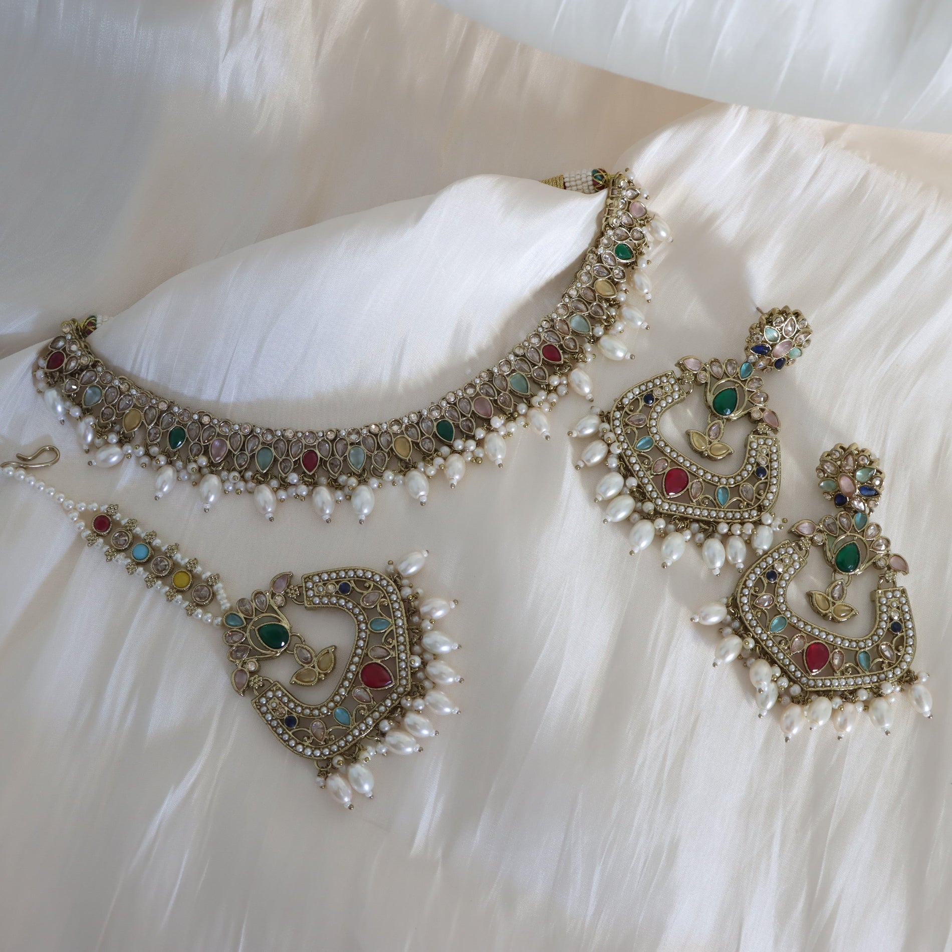 Ornate necklace and earrings on a white fabric background