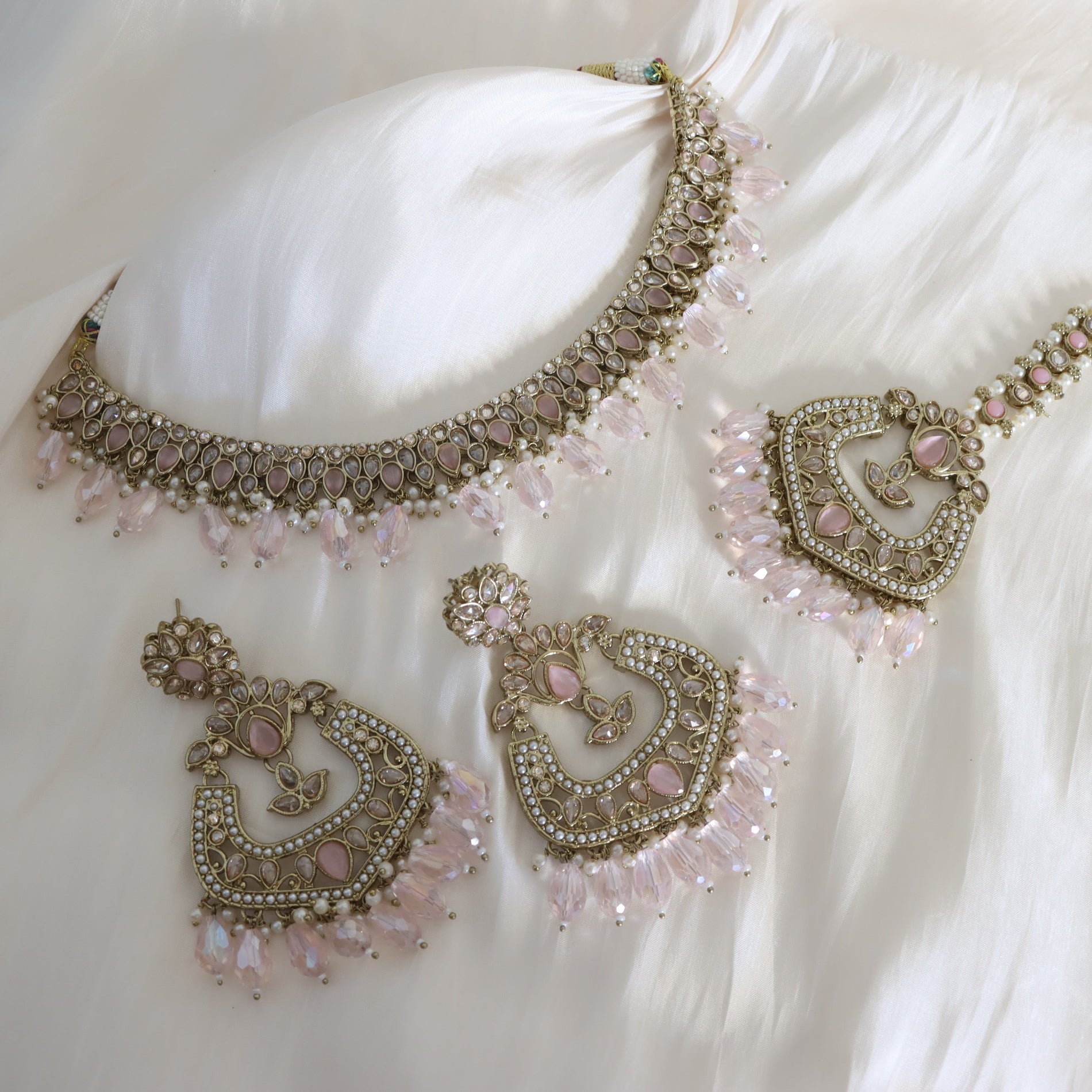 Ornate jewelry set with necklace and earrings on a white fabric background