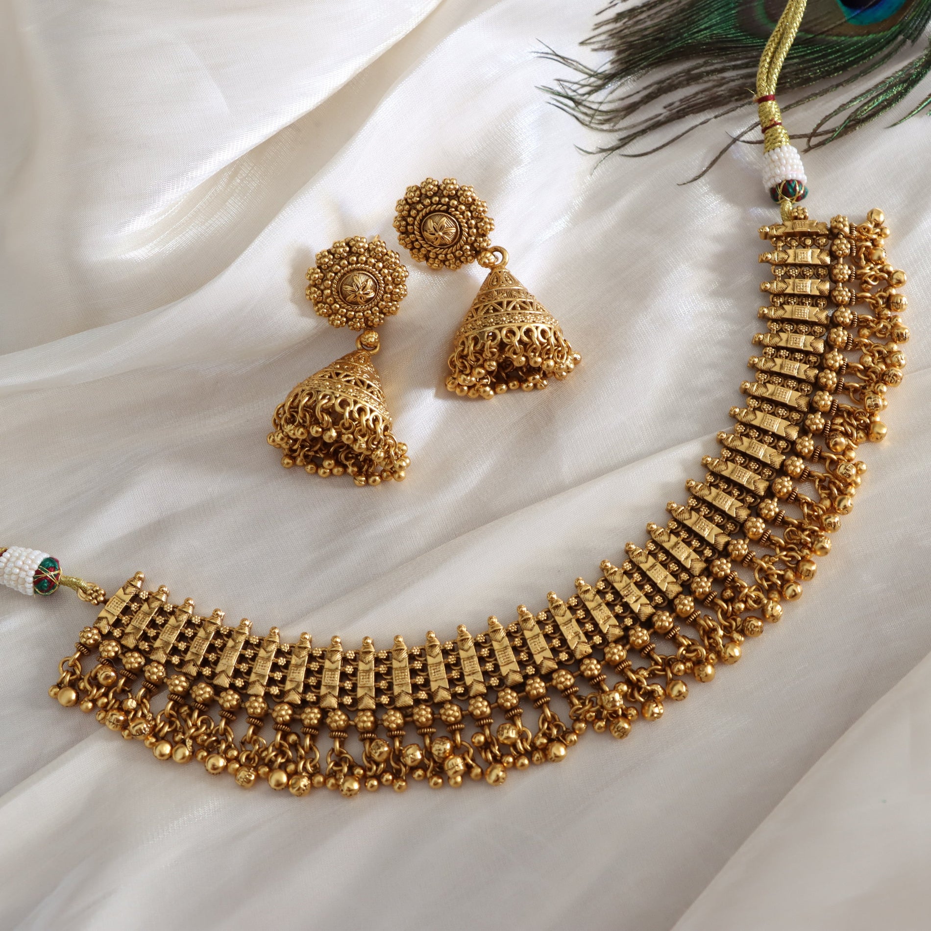 Gold necklace and earrings on a white fabric background