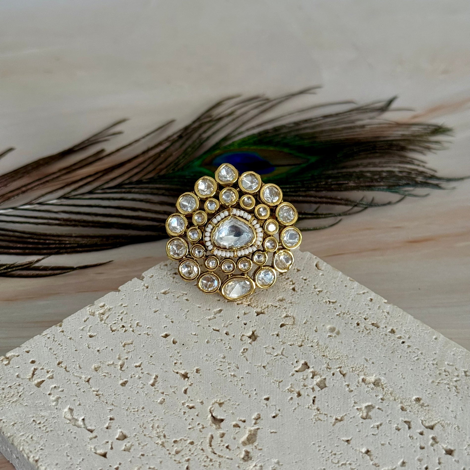 Decorative brooch with peacock feather on a textured surface