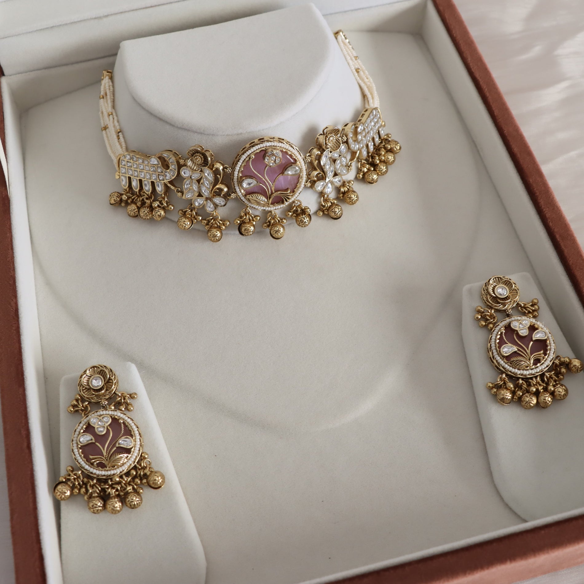 Gold-toned traditional jewelry set including a choker necklace and matching earrings, displayed on cream-colored jewelry stands inside a brown presentation box.