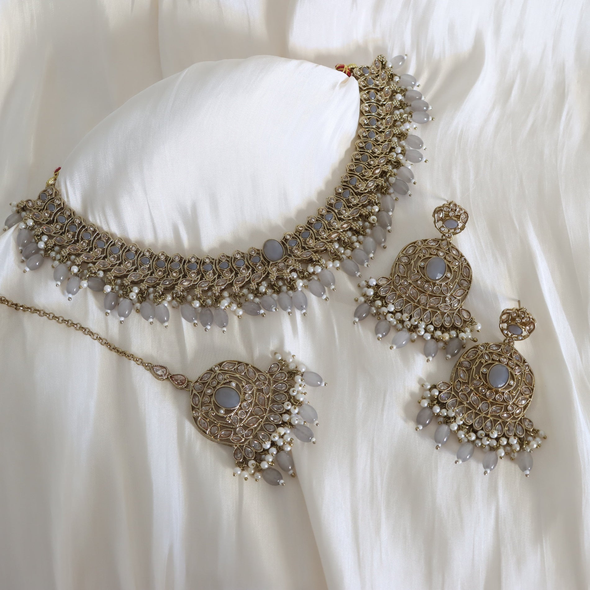 Ornate necklace and earrings set on a white fabric background