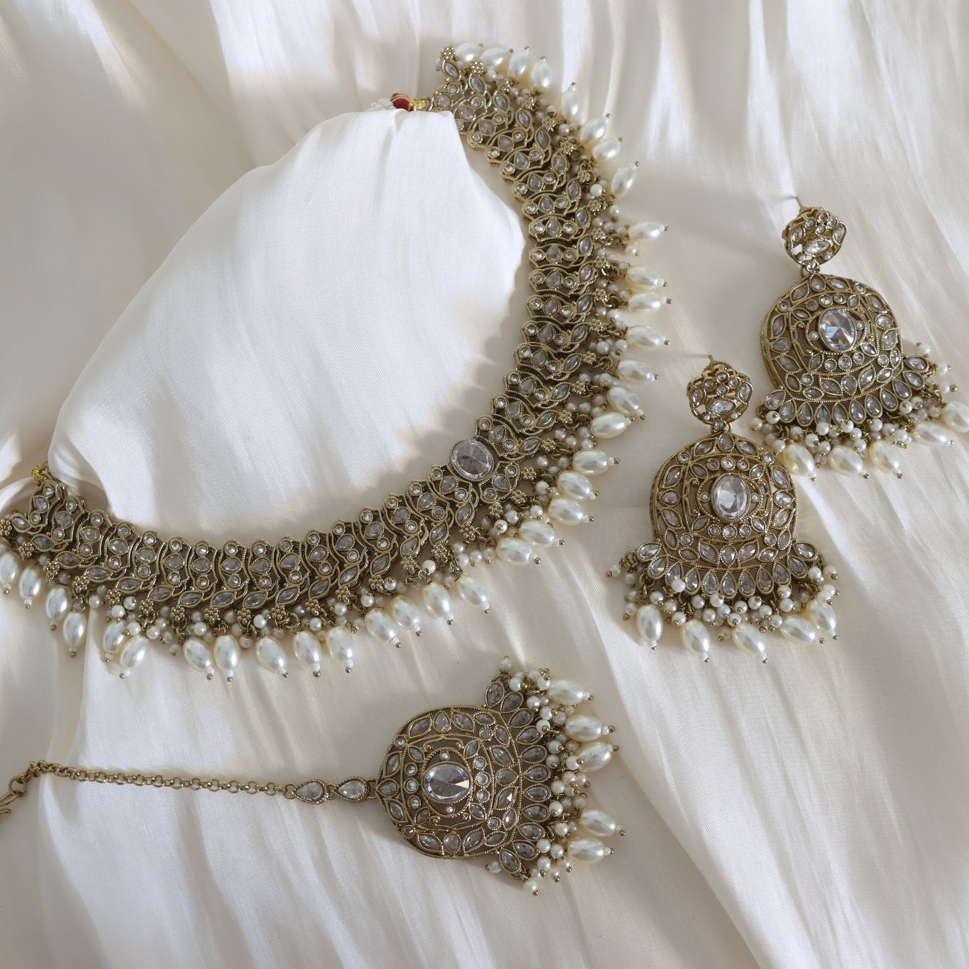 Ornate necklace with matching earrings on a white fabric background