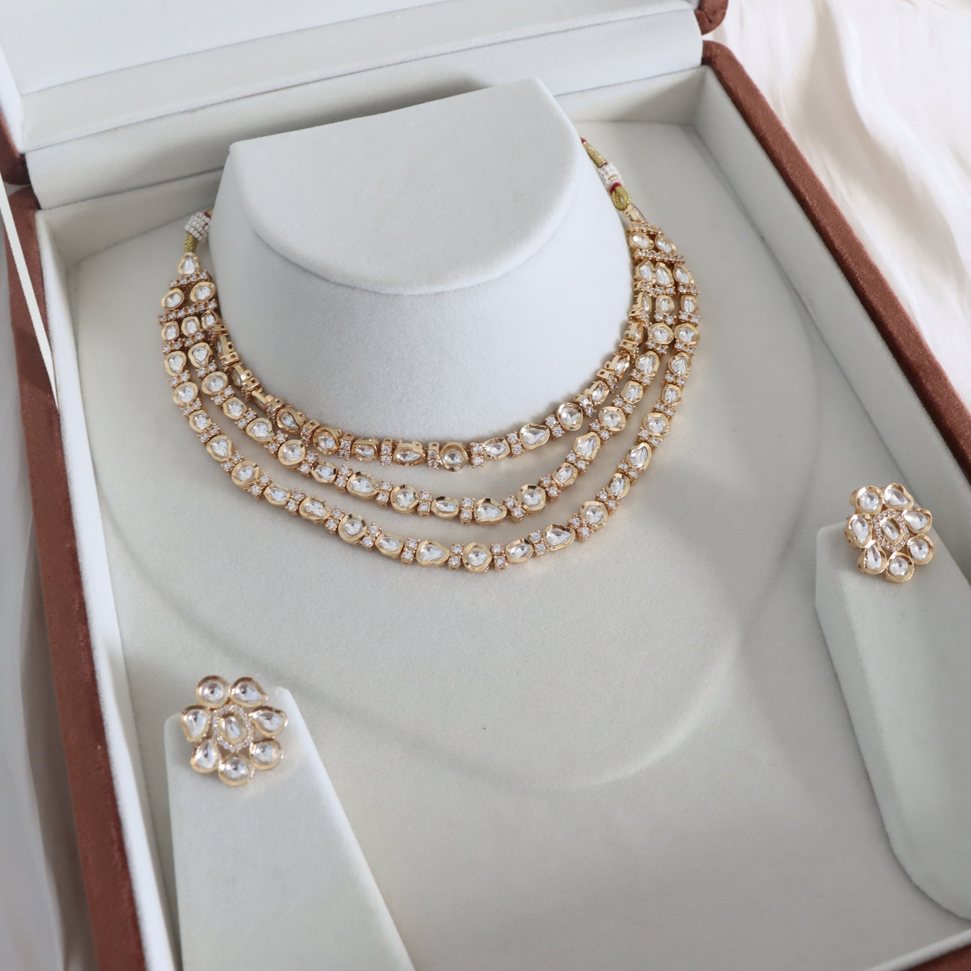 Jewelry set with necklace and earrings on a mannequin bust in an open jewelry box.