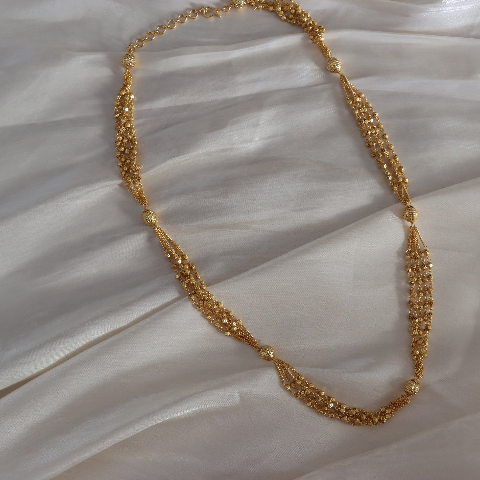 Gold necklace on a textured white surface