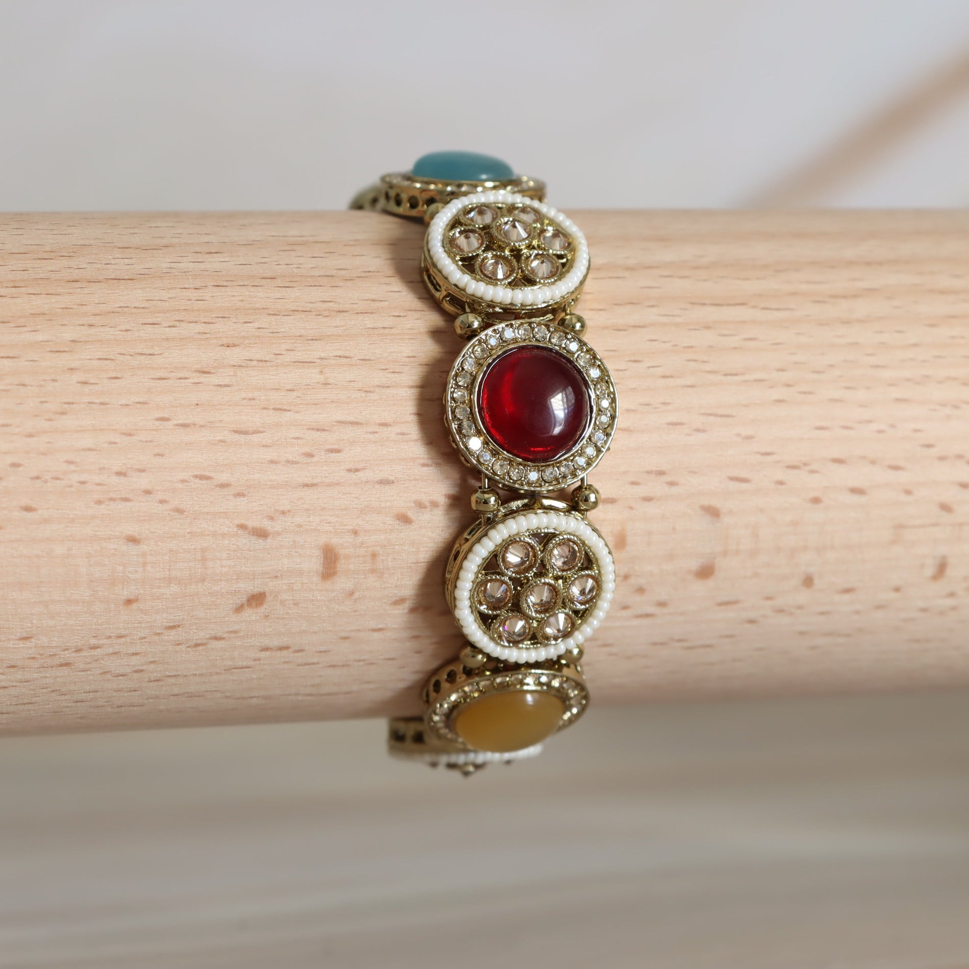 Gold bracelet with gemstones on a wooden surface