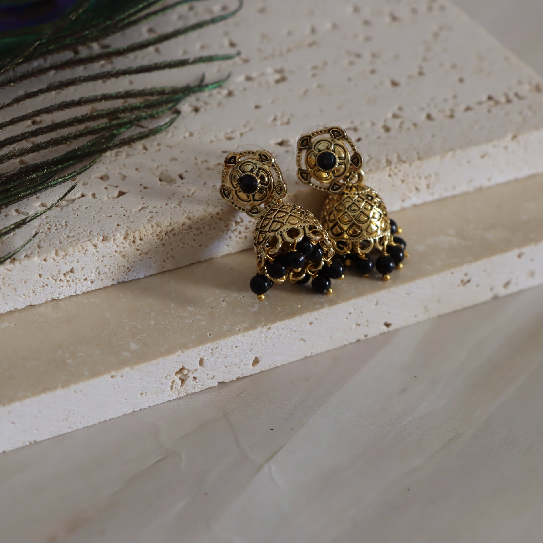 Gold and black turtle-shaped earrings on a textured surface