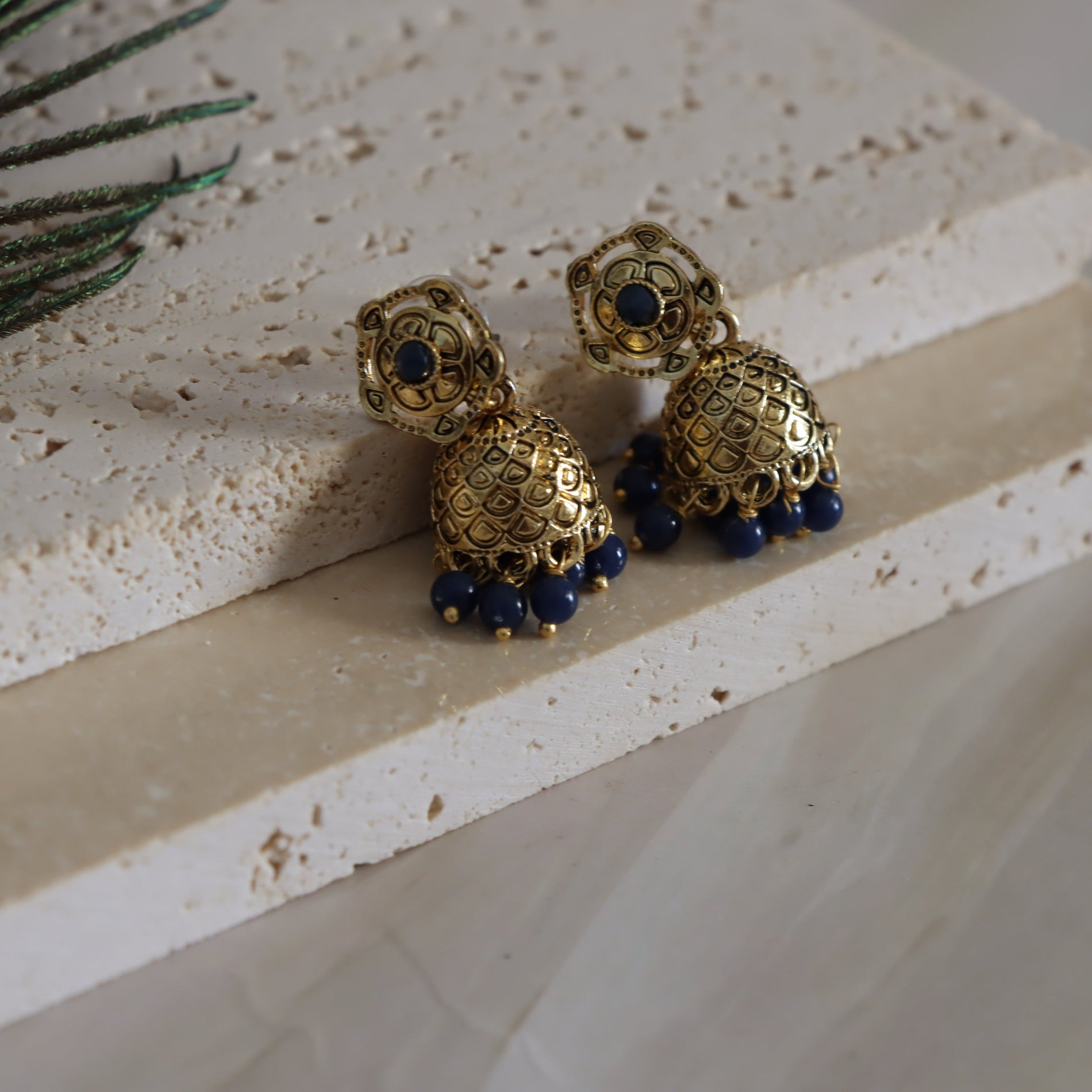 Gold and blue turtle-shaped earrings on a textured surface