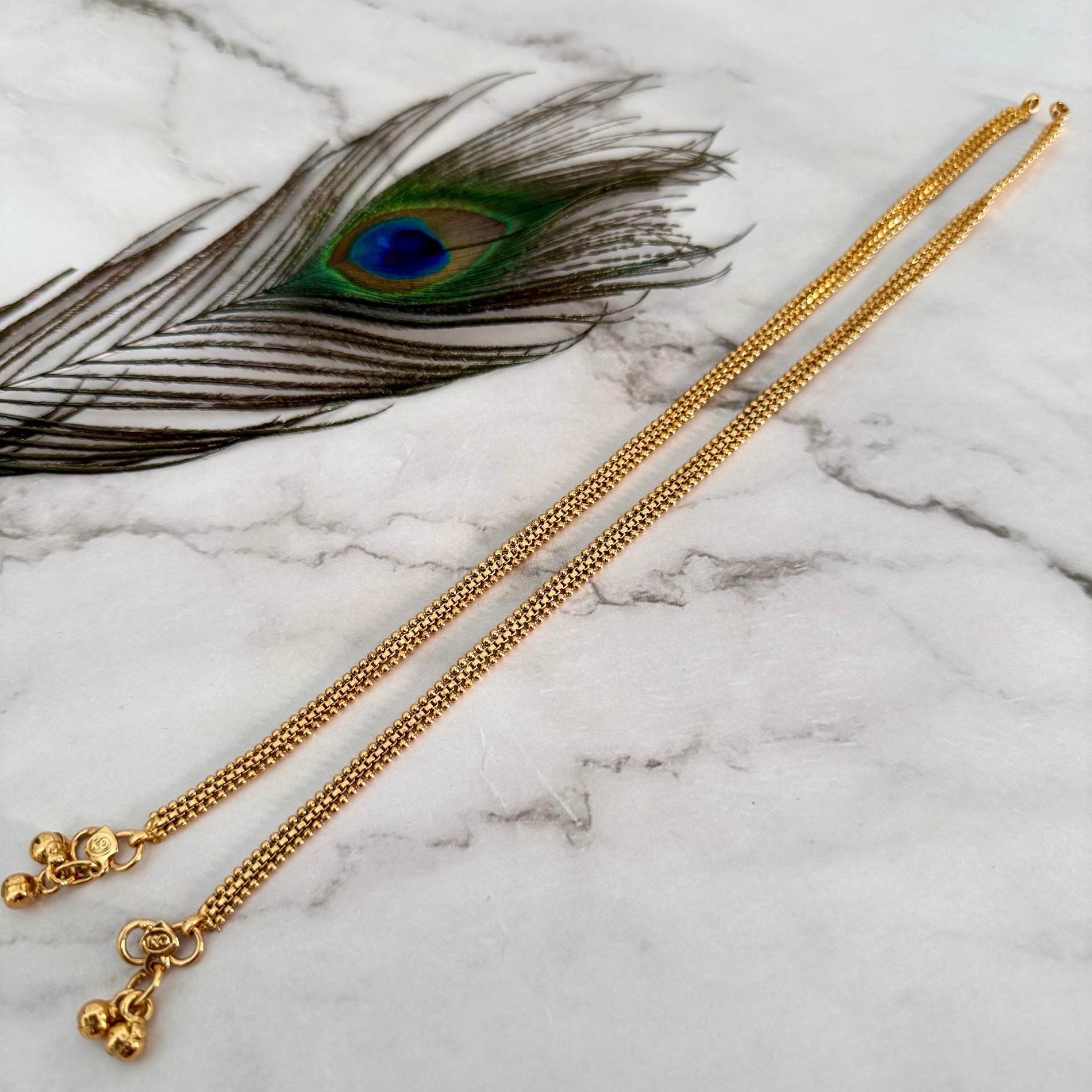 Gold anket on a marble surface and decorative peacock feather