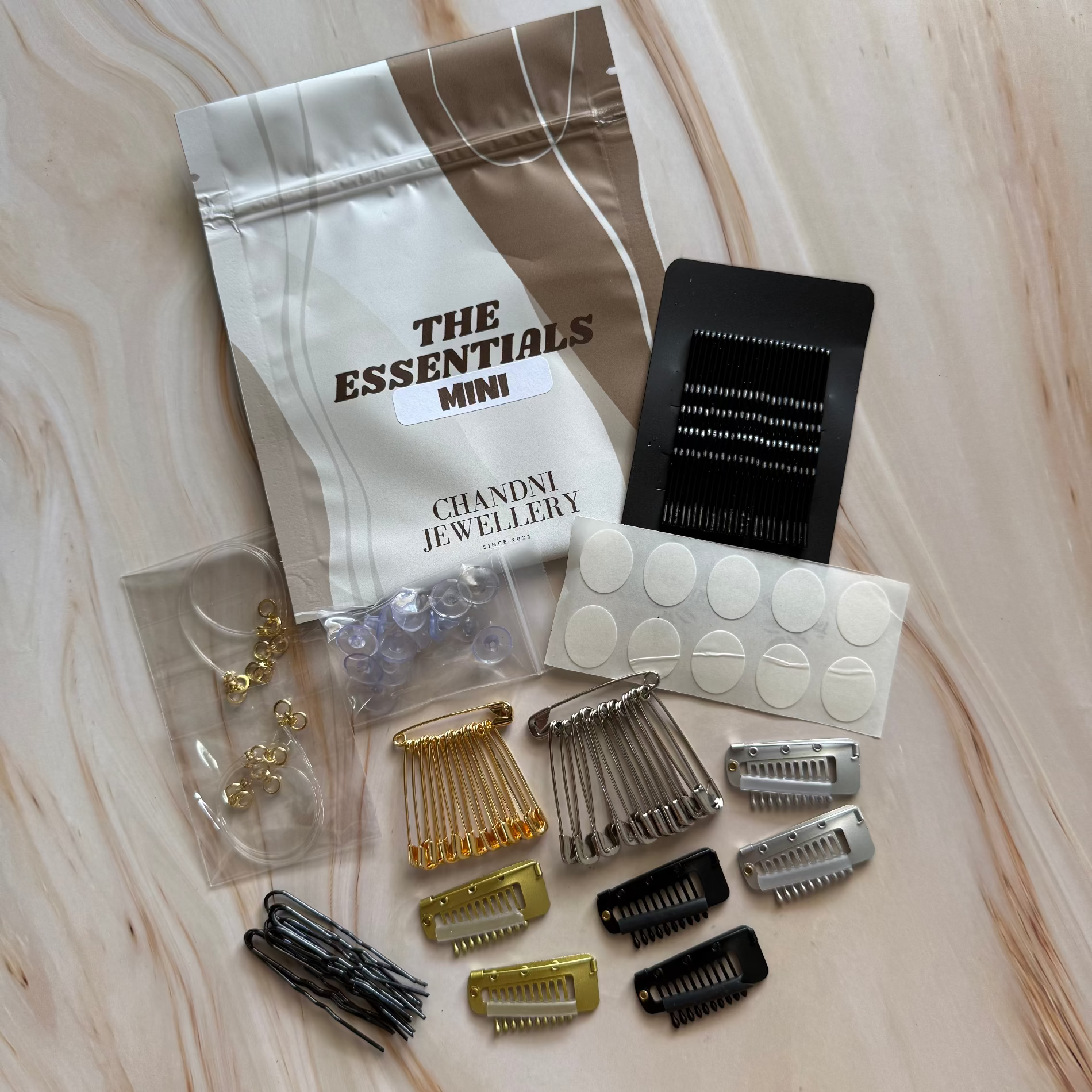 Collection of hair accessories including clips and pins on a wooden surface with 'The Essentials Mini' packaging.