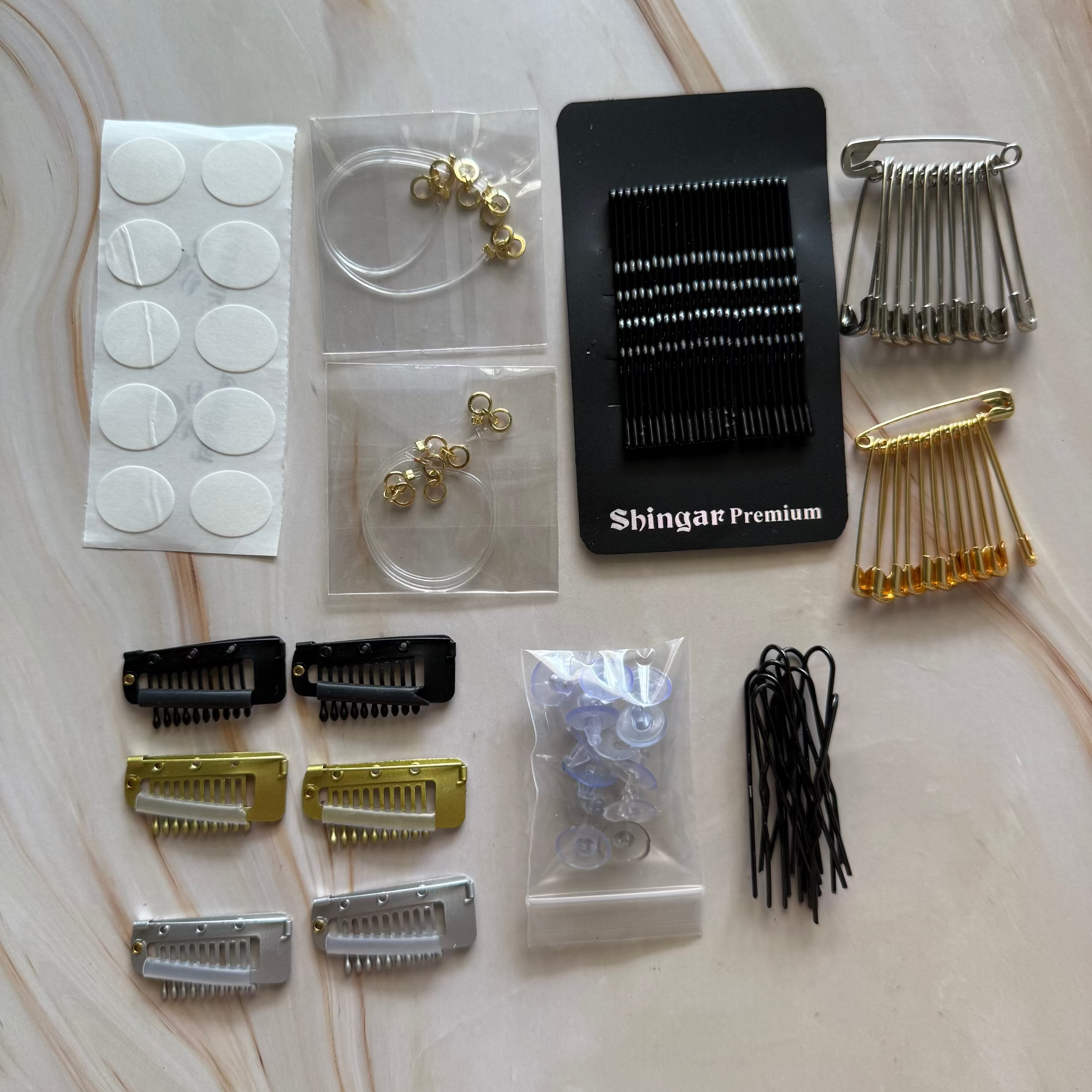 Collection of hair styling tools including clips, combs, and attachments on a marble surface.