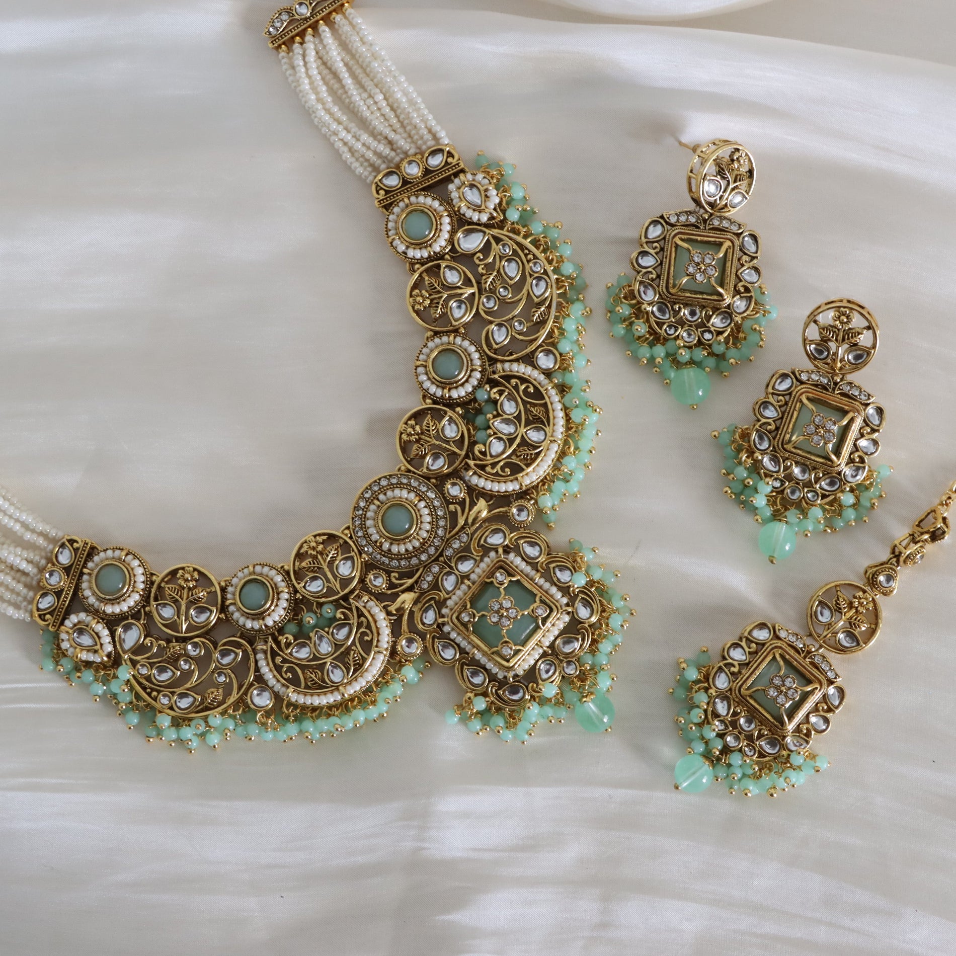 Ornate gold and turquoise jewelry set on a white fabric background