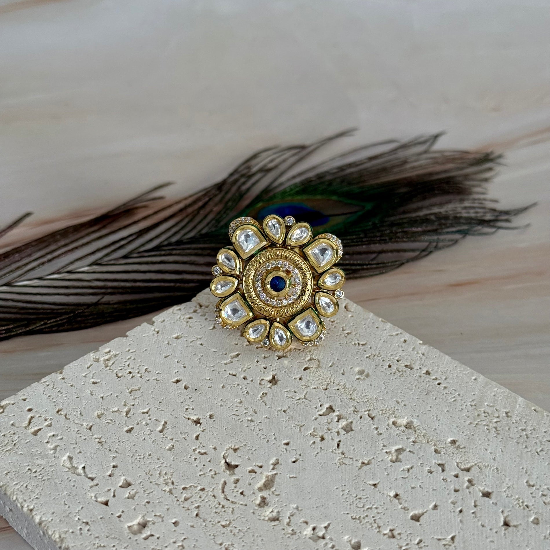 Decorative ring with peacock feather on a textured surface