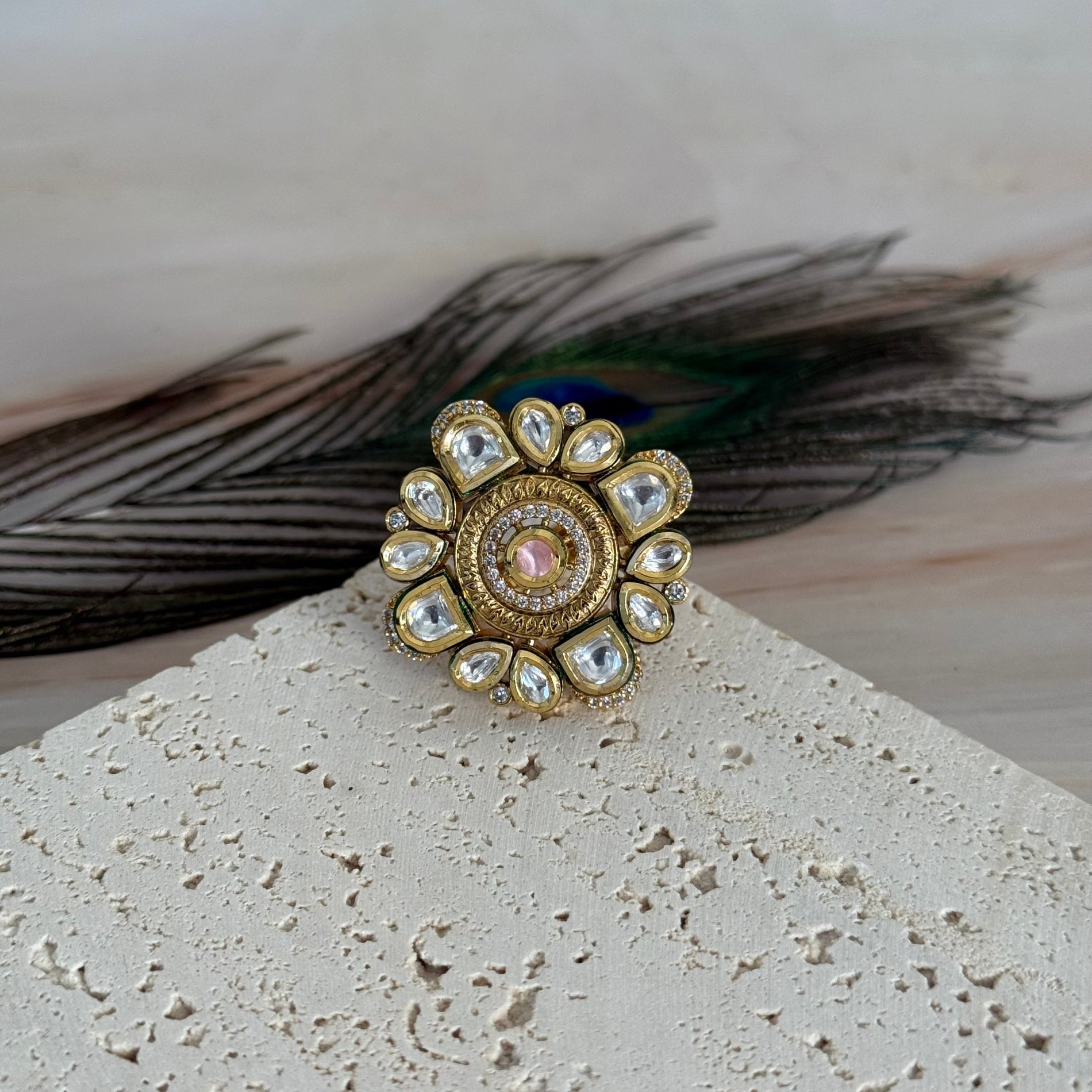 Decorative brooch with gemstones on a textured surface with peacock feathers