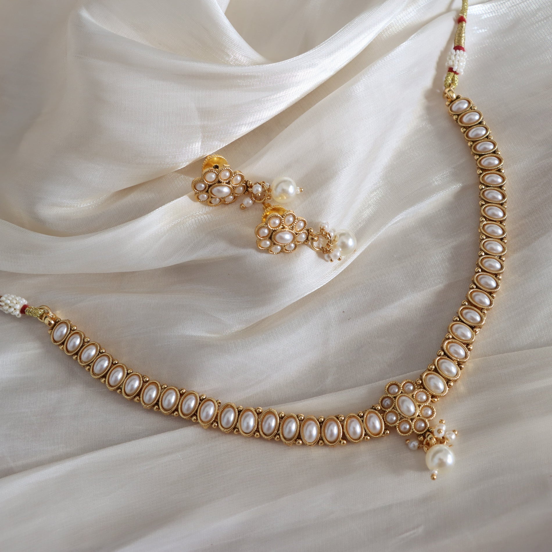Gold necklace with pearls on a white fabric background