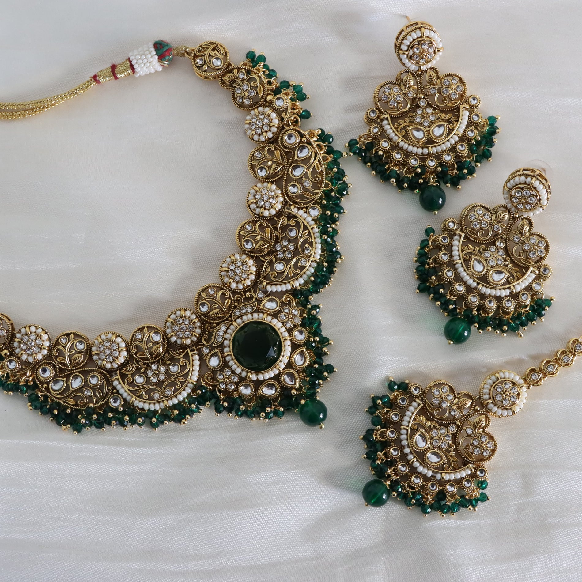 Ornate gold and green jewelry set on a white background