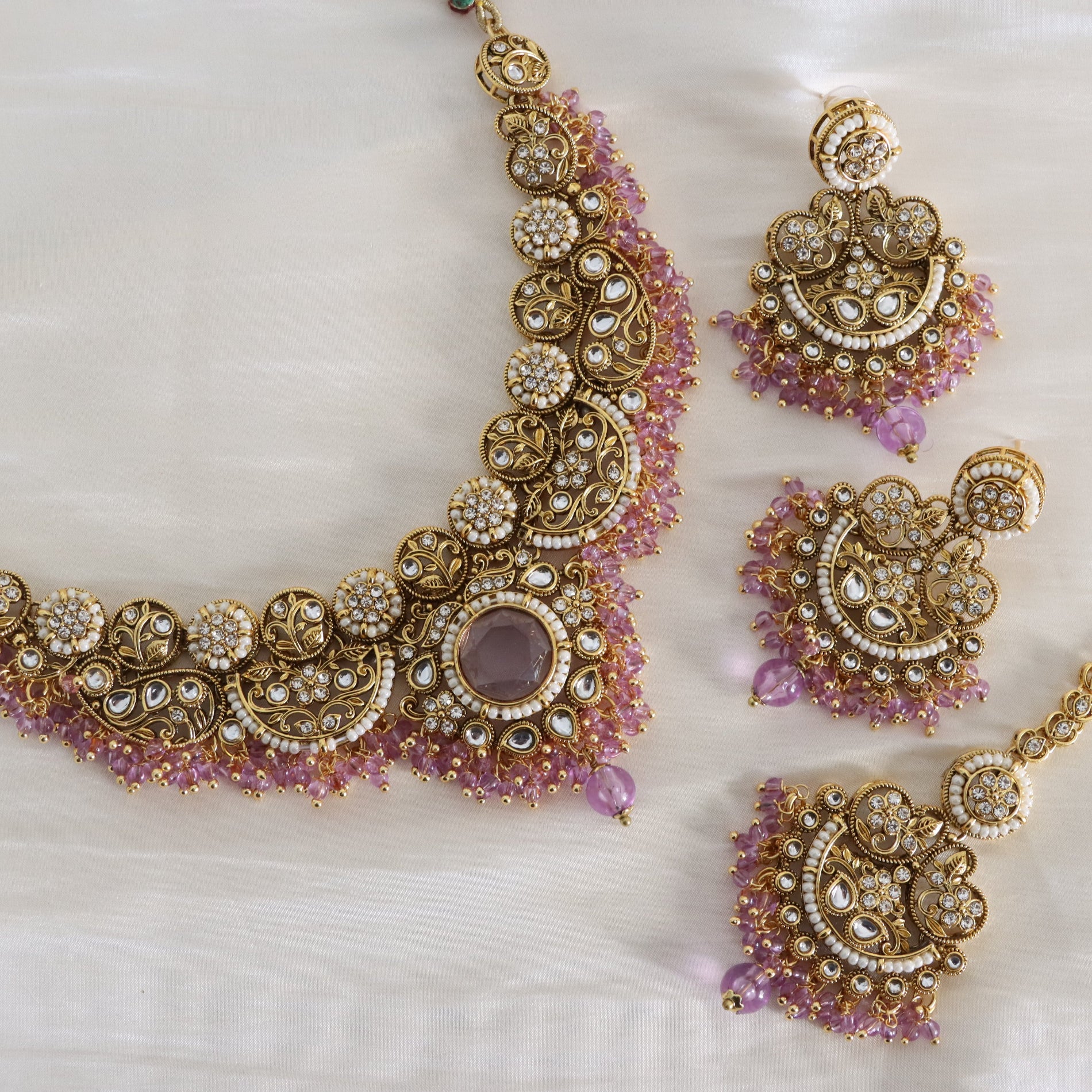 Ornate gold and pink jewelry set on a light background