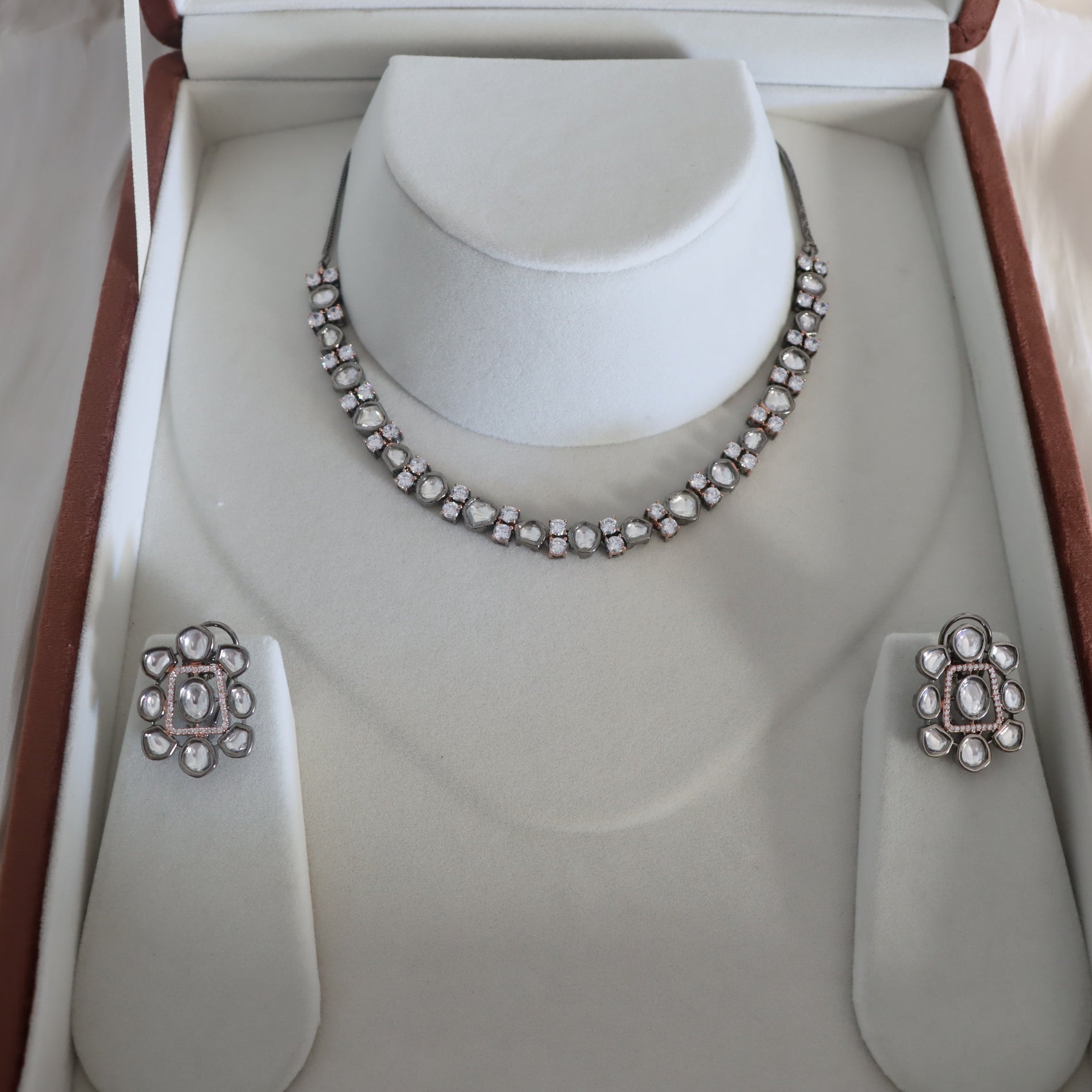 Silver necklace and earrings set on a mannequin bust in an open jewelry box.