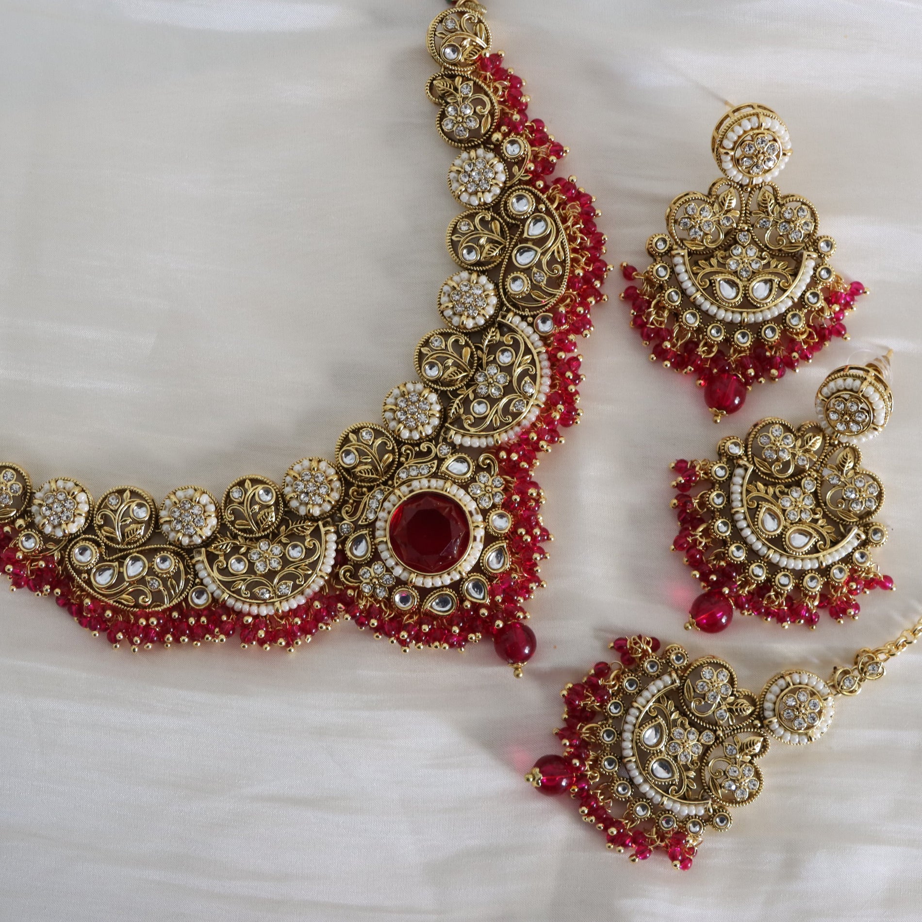 Gold and red jewelry set on a white background