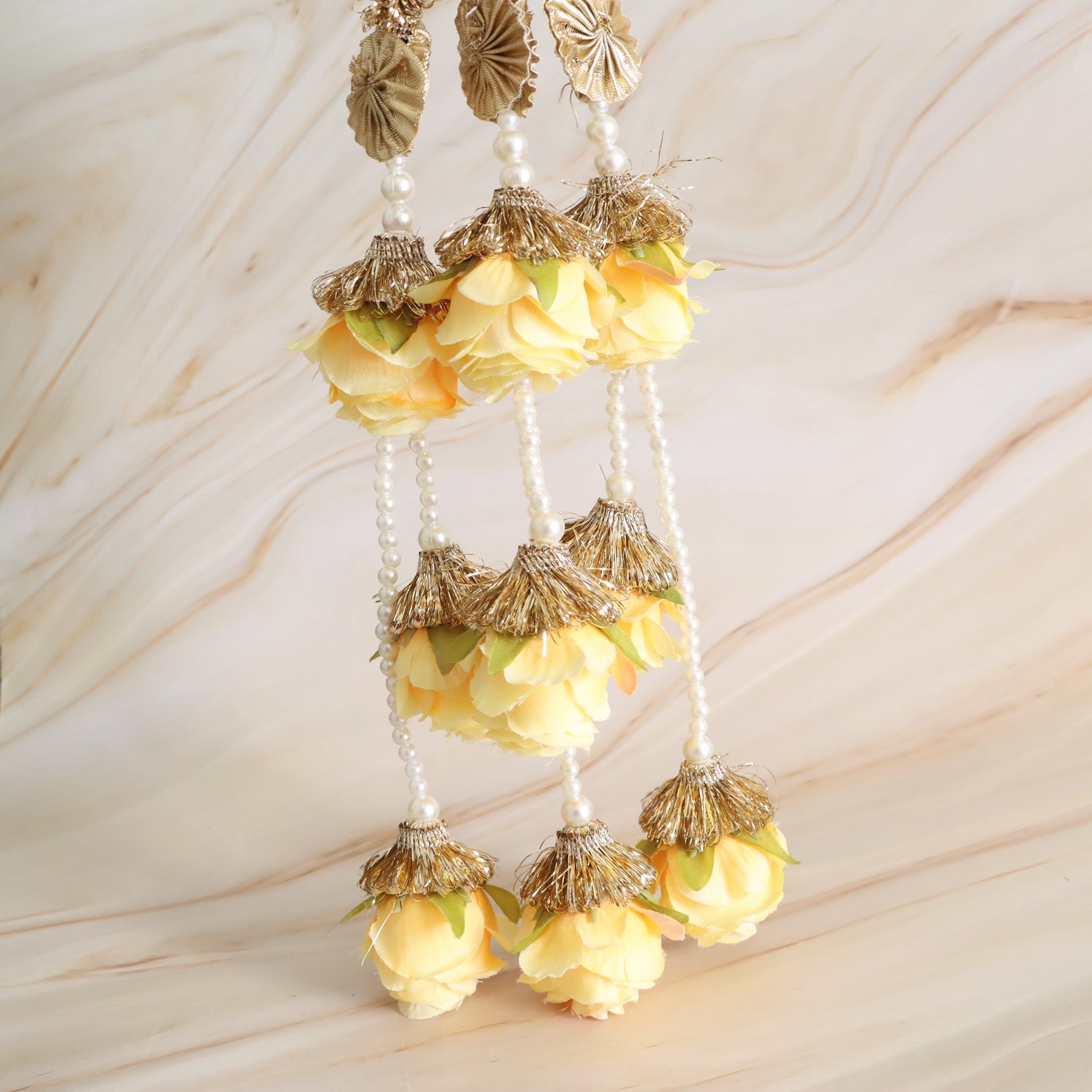 Decorative hanging with yellow flowers and gold accents on a beige background