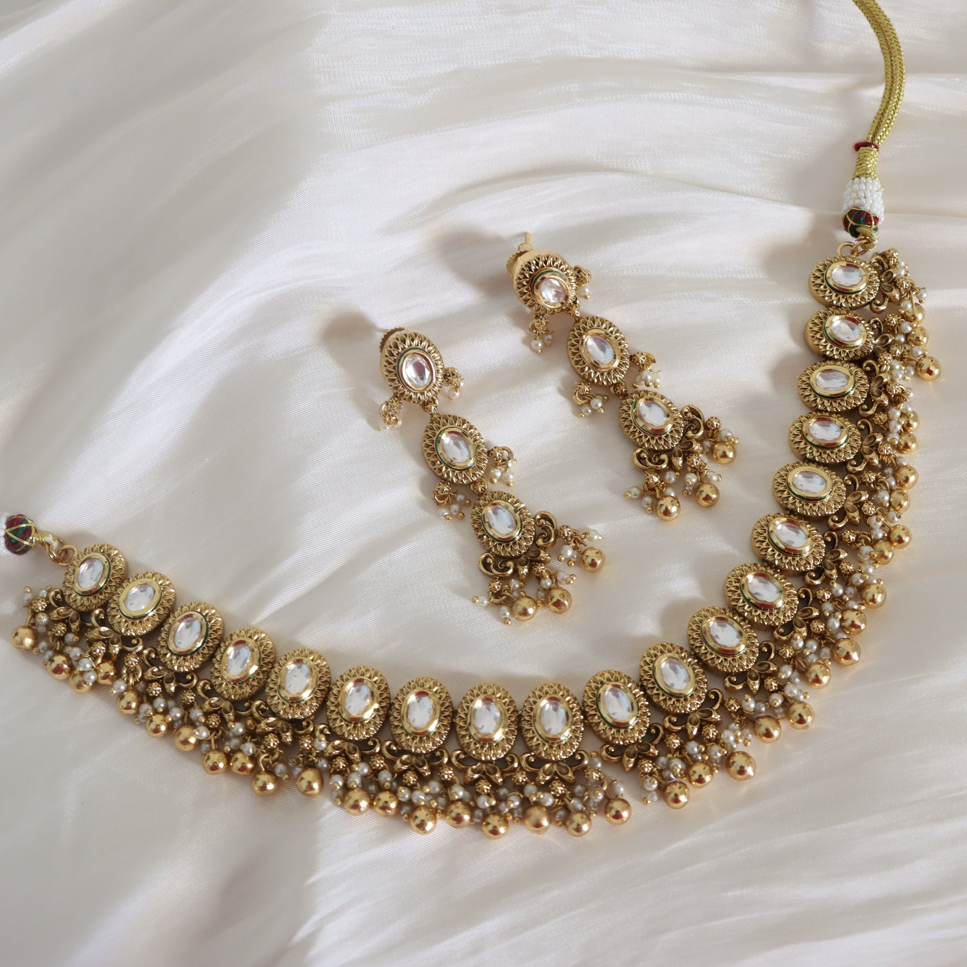 Gold necklace and earrings on a white fabric background